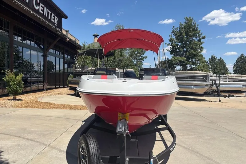 Slide: The Image of 2025 Tahoe T21 boat with red canopy on trailer, displayed outdoors at a sales center. - 2