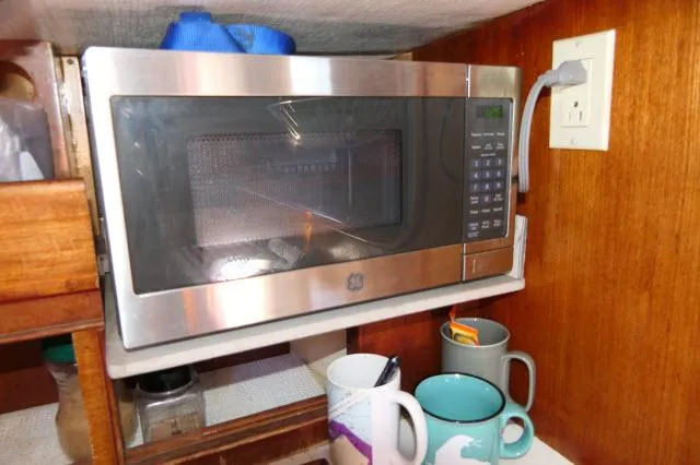 Slide: The Image of Microwave in a Peterson 44 yacht kitchen, with mugs and wooden cabinetry, 1976 model. - 14