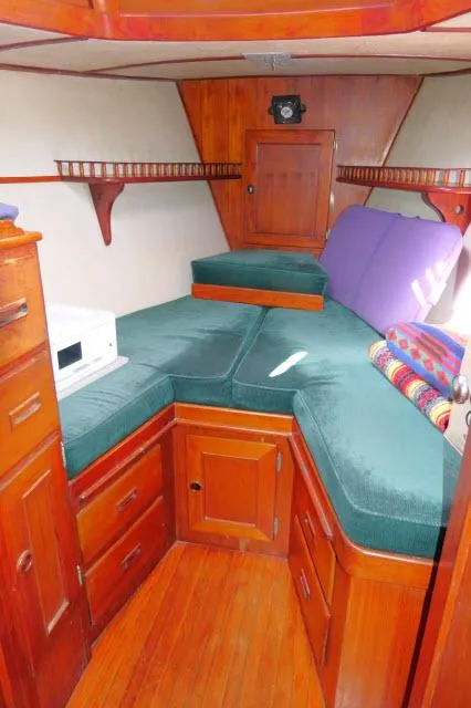 Slide: The Image of 1976 Peterson 44 yacht interior with wooden cabinetry and green cushions. - 19