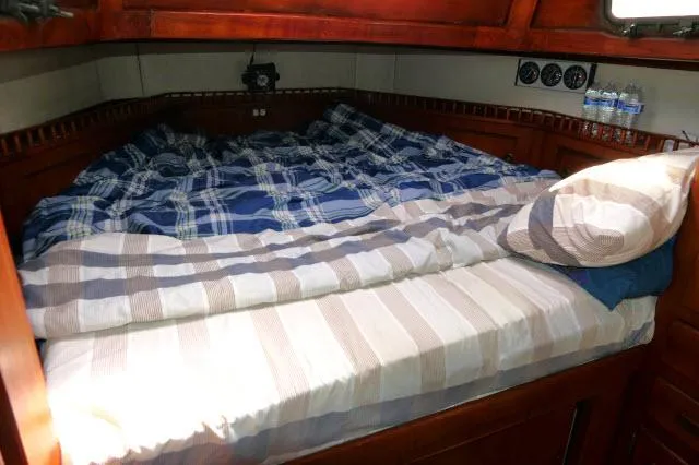Slide: The Image of Cozy cabin bed in a 1976 Peterson 44 sailboat with plaid bedding. - 25