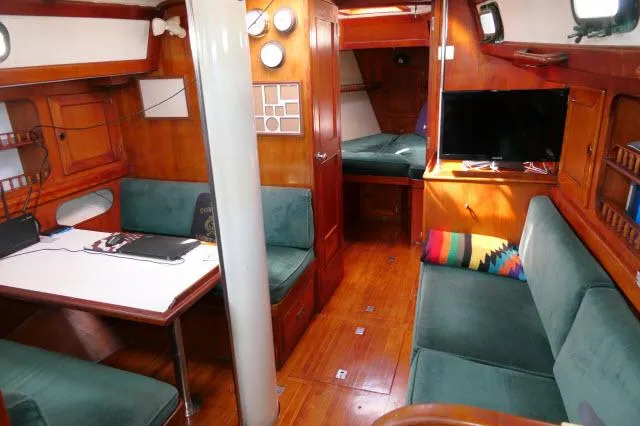 Slide: The Image of Interior of a 1976 Peterson 44 sailboat with wood paneling and green seating. - 3
