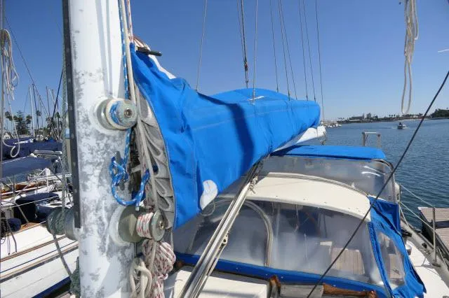 Slide: The Image of 1976 Peterson 44 sailboat with blue sail cover, docked in sunny marina. - 37