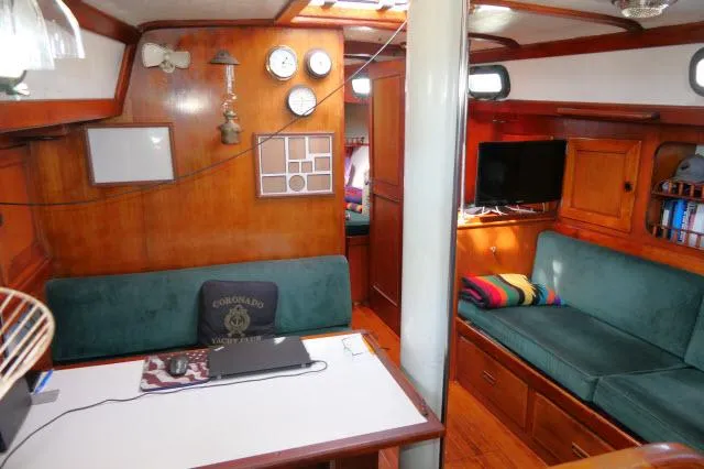 Slide: The Image of 1976 Peterson 44 yacht interior with wood paneling, green seating, and nautical decor. - 4