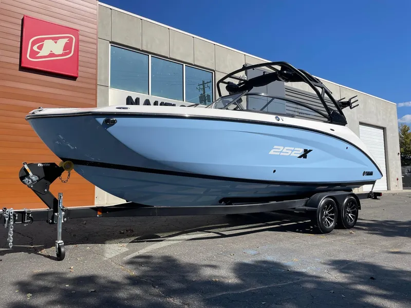 Slide: The Image of 2024 Yamaha Boats 252XE, blue, on trailer outside dealership. - 1