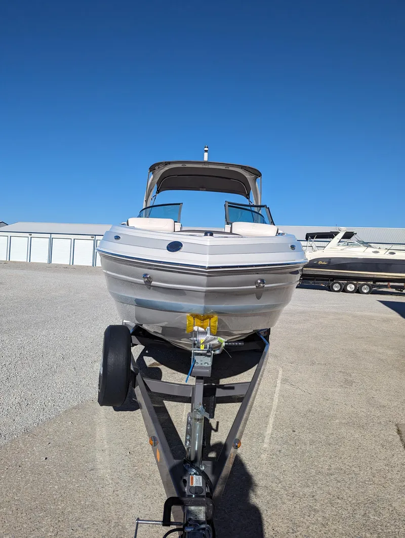 Slide: The Image of 2023 Crownline 260 SS boat on trailer, parked outdoors under clear blue sky. - 13