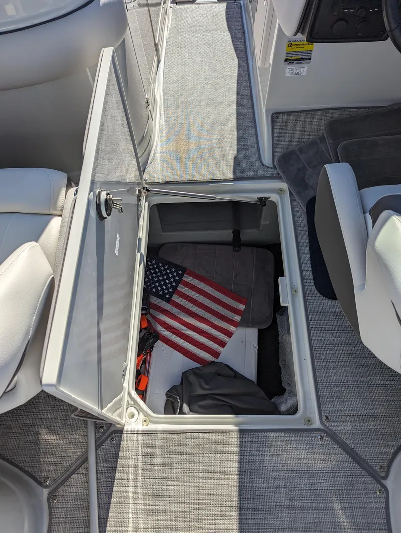 Slide: The Image of 2023 Crownline 260 SS boat interior with open storage compartment and American flag. - 33