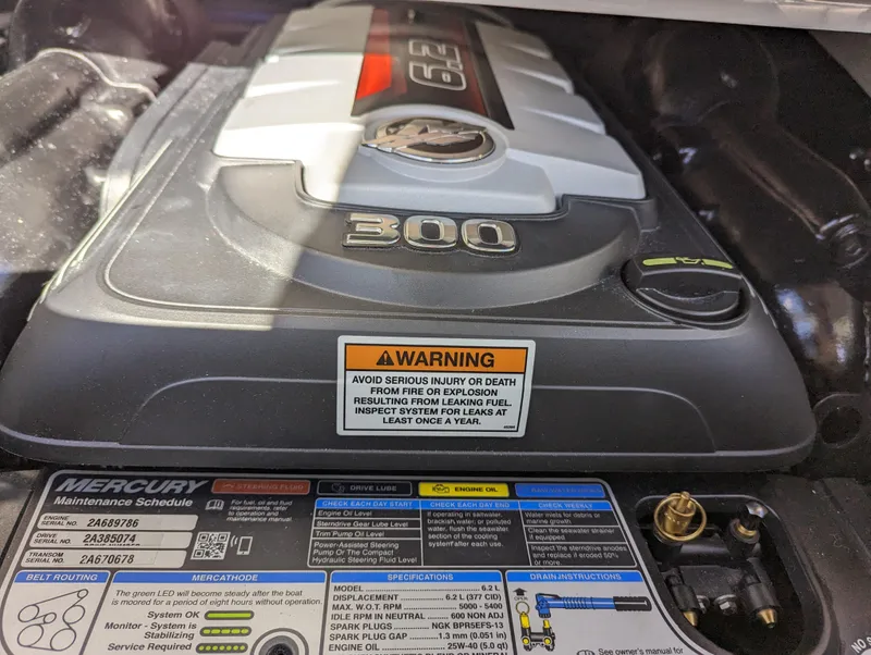 Slide: The Image of Engine of 2023 Crownline 260 SS boat with warning label and maintenance schedule. - 35