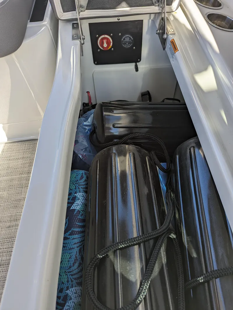 Slide: The Image of 2023 Crownline 260 SS boat storage compartment with black fenders and safety equipment. - 37