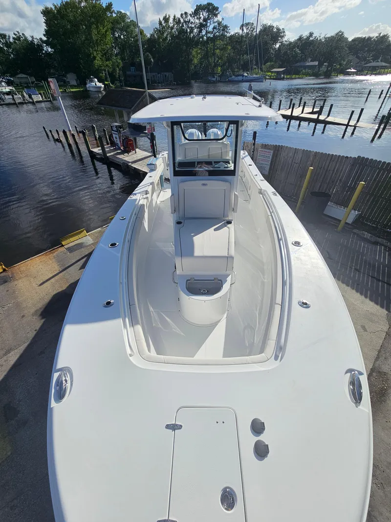 Slide: The Image of 2025 Sea Hunt Gamefish 28 CB boat docked by a serene waterfront. - 2