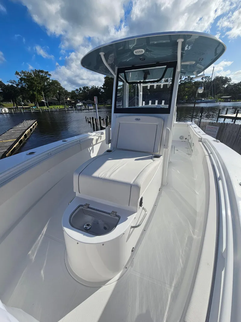 Slide: The Image of 2025 Sea Hunt Gamefish 28 CB boat docked by a scenic waterfront. - 23