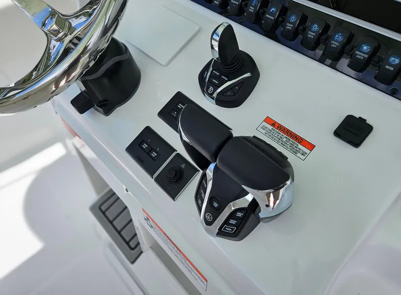 Slide: The Image of Control panel of 2025 Sea Hunt Gamefish 28 CB boat with steering and throttle controls. - 13