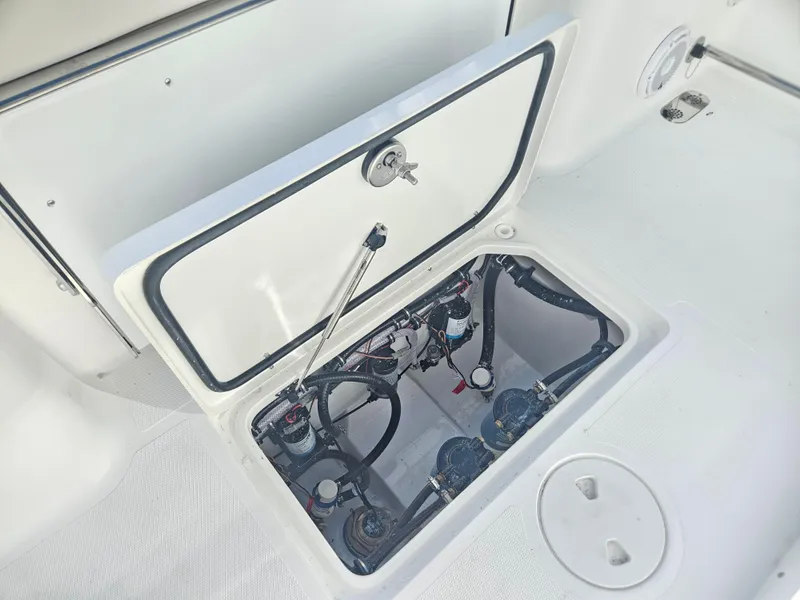 Slide: The Image of 2025 Sea Hunt Gamefish 28 CB boat compartment with open hatch and visible wiring. - 20