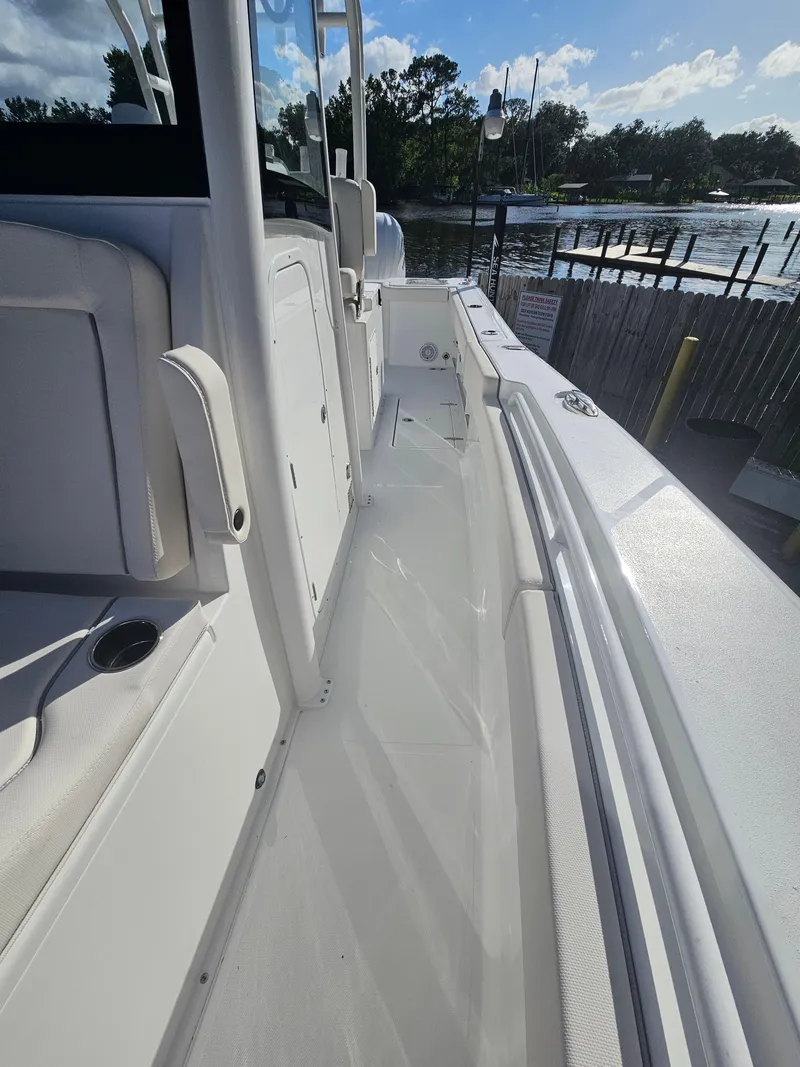 Slide: The Image of 2025 Sea Hunt Gamefish 28 CB boat, white deck, docked by a scenic waterfront. - 27