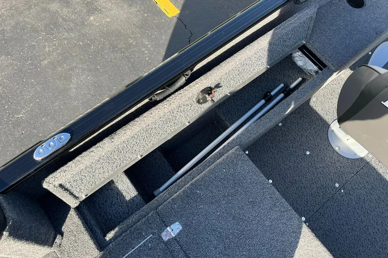 Slide: The Image of 2025 Lund 1650 Rebel XL SS boat interior with storage compartment and fishing rod holders. - 21