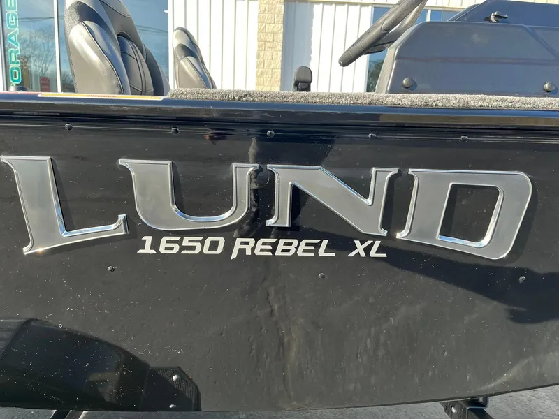 Slide: The Image of 2025 Lund 1650 Rebel XL SS boat, black exterior with logo and seating visible. - 23