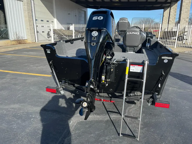 Slide: The Image of 2025 Lund 1650 Rebel XL SS boat with outboard motor and ladder, parked outdoors. - 5