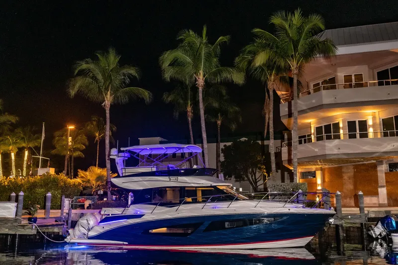Slide: The Image of 2022 Regal 42 FXO yacht docked at night, illuminated by blue lights. - 21