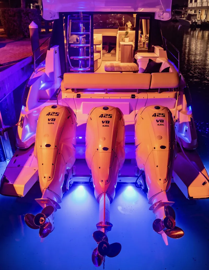 Slide: The Image of 2022 Regal 42 FXO boat with triple outboard engines, illuminated by blue lights at night. - 22