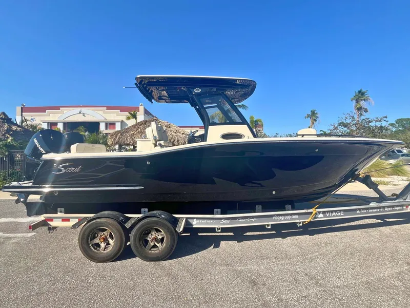 The Image of 2025 Scout 277 LXF boat on trailer, sleek black design, sunny day background. - 0