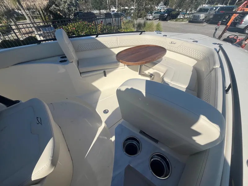 Slide: The Image of 2025 Scout 277 LXF boat interior with seating and table in sunlight. - 14