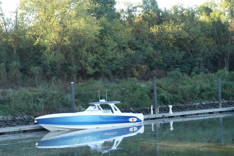 Slide: The Image of 2014 Cigarette 42 Huntress boat docked by a forested shoreline. - 1