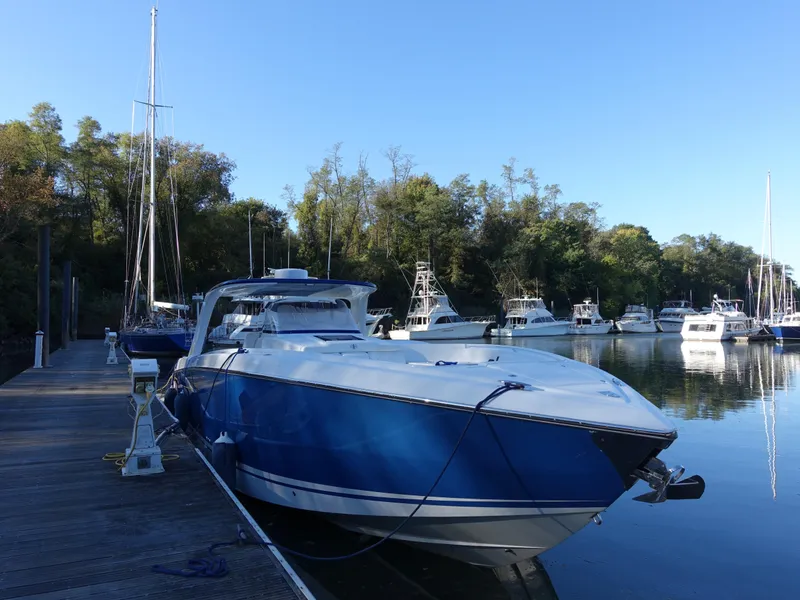 Slide: The Image of 2014 Cigarette 42 Huntress boat docked in a serene marina setting. - 2