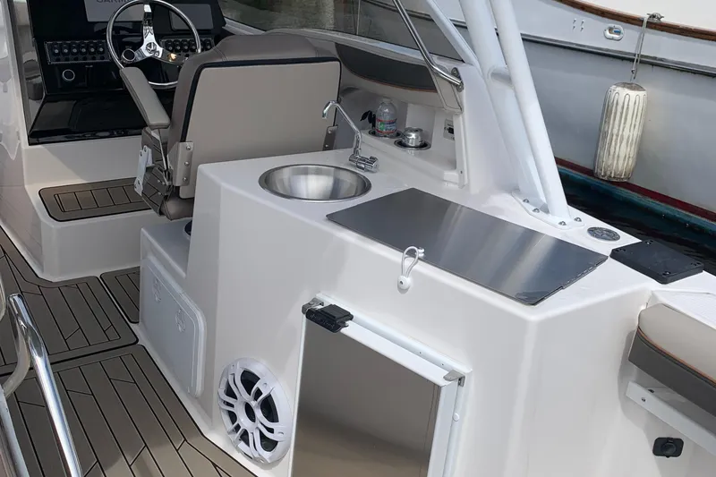 Slide: The Image of 2022 Cutwater C-24 DC boat interior with helm, sink, and seating area. - 3
