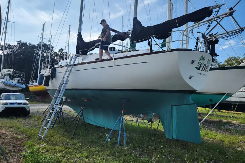 Slide: The Image of 1979 Morgan 45 Ketch sailboat on land with a person standing on deck. - 10