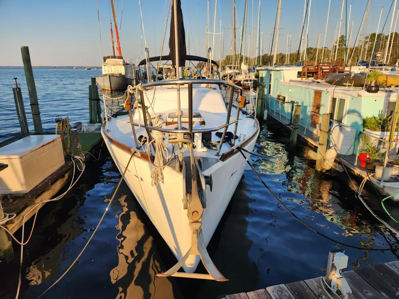 Slide: The Image of 1979 Morgan 45 Ketch sailboat docked at marina, surrounded by calm water and other boats. - 2