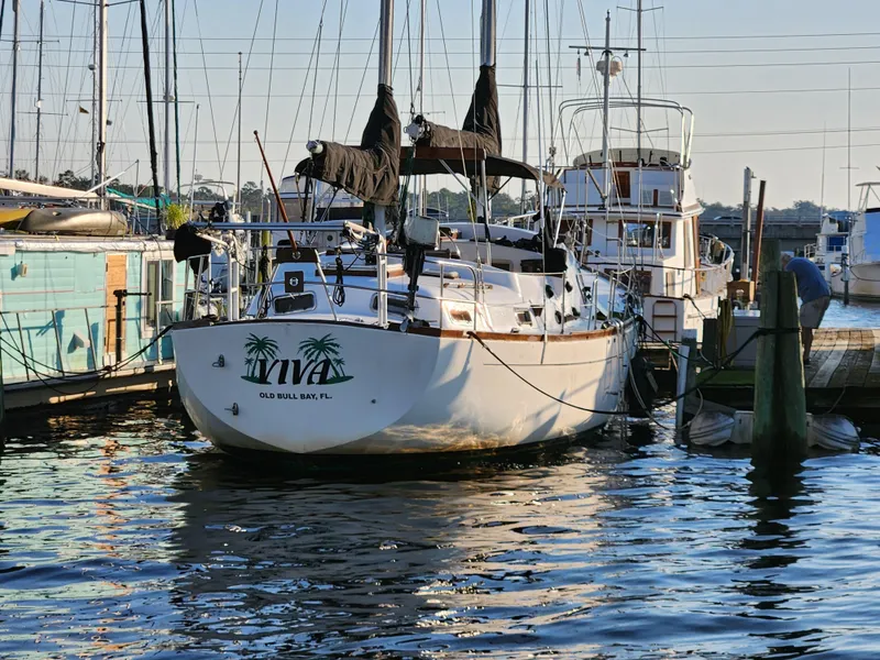 Slide: The Image of 1979 Morgan 45 Ketch sailboat docked at marina, reflecting on calm water. - 3
