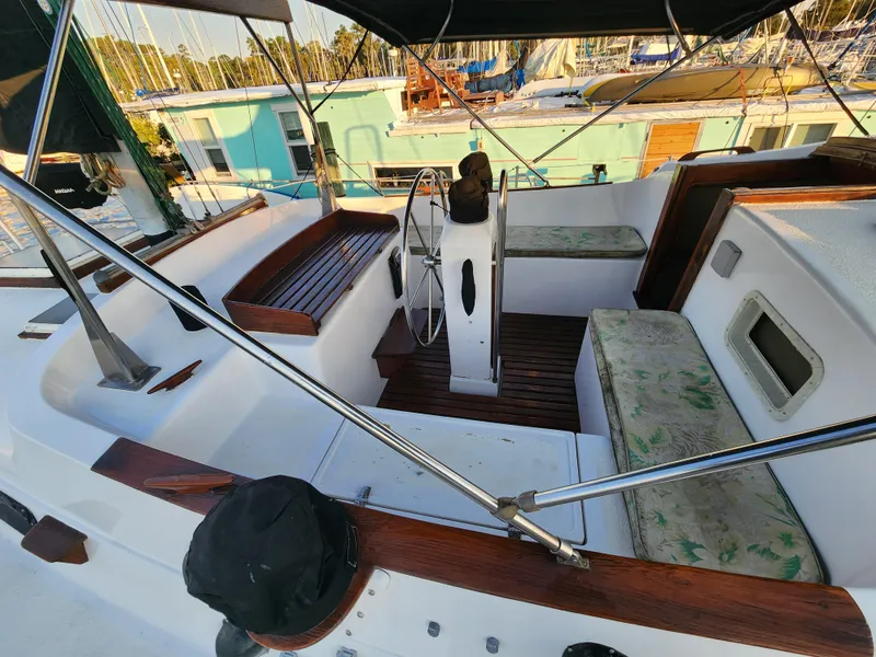 Slide: The Image of 1979 Morgan 45 Ketch sailboat cockpit with wooden accents and seating, docked at marina. - 30