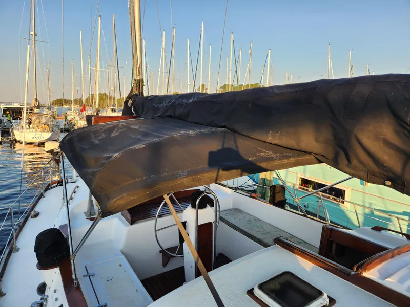 Slide: The Image of 1979 Morgan 45 Ketch sailboat docked in a marina, featuring a covered cockpit. - 36