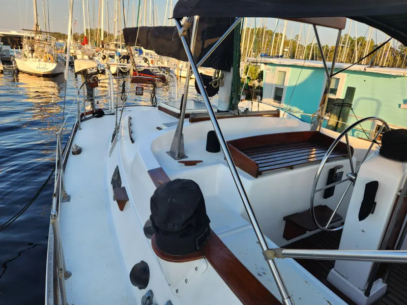 Slide: The Image of 1979 Morgan 45 Ketch sailboat docked in a marina, featuring a spacious deck and steering wheel. - 37