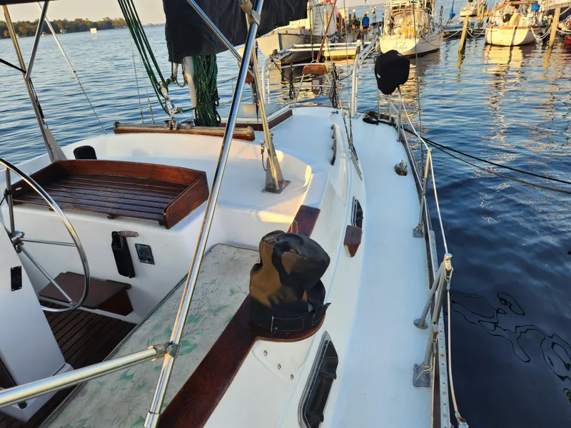 Slide: The Image of 1979 Morgan 45 Ketch sailboat docked on calm water, featuring a spacious deck and steering wheel. - 38