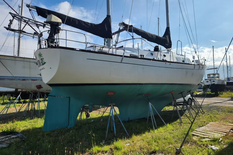 Slide: The Image of 1979 Morgan 45 Ketch sailboat on land, supported by stands, under a clear blue sky. - 6