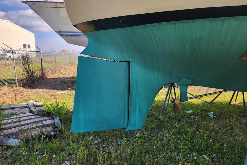Slide: The Image of 1979 Morgan 45 Ketch sailboat hull and rudder on land, with green paint. - 7