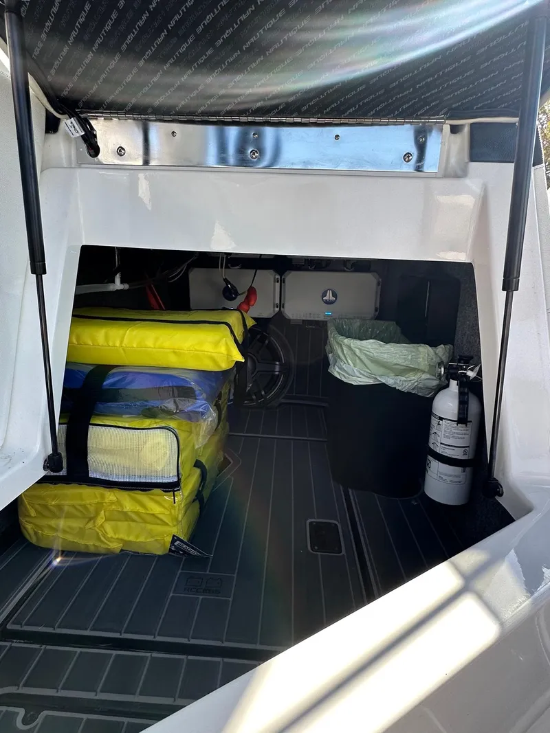 Slide: The Image of 2023 Nautique PARAGON 23 storage area with safety equipment and supplies. - 18