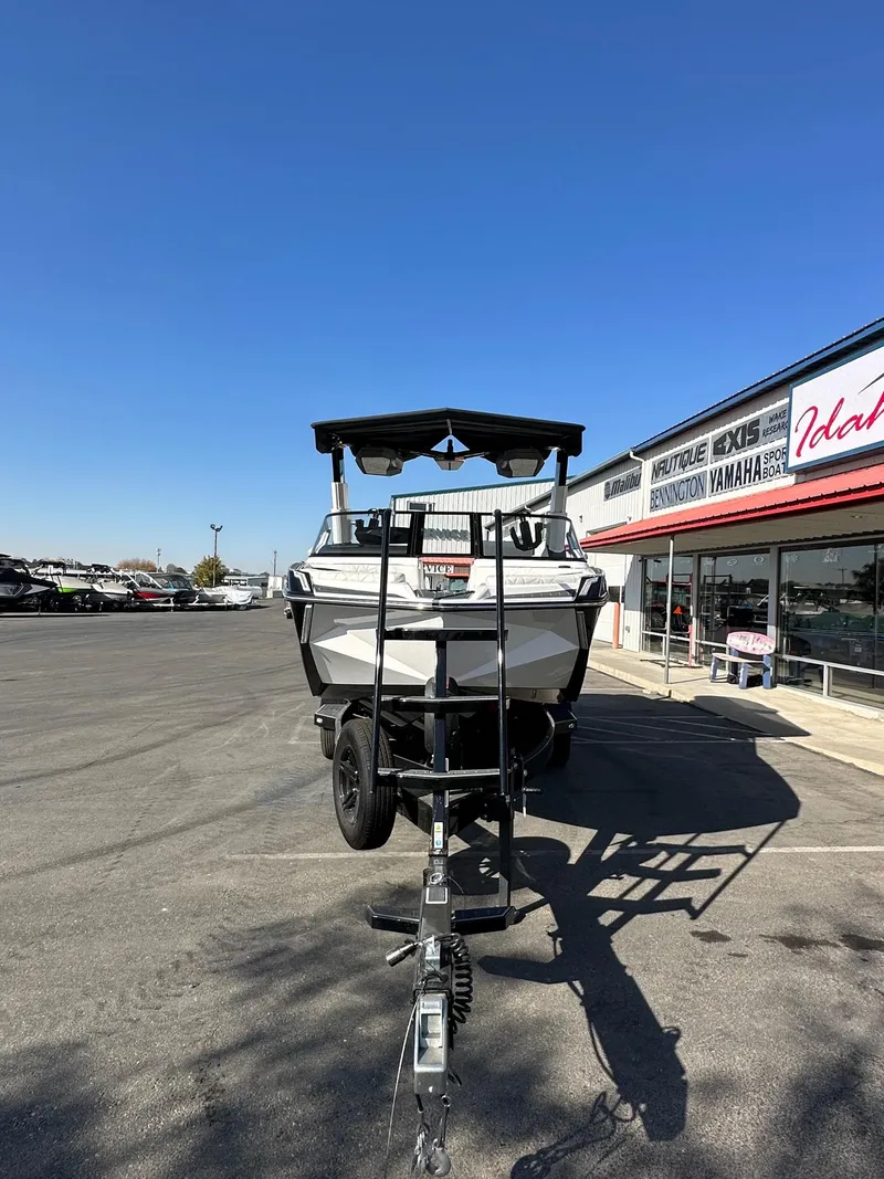 Slide: The Image of 2023 Nautique PARAGON 23 boat on trailer at dealership under clear blue sky. - 5