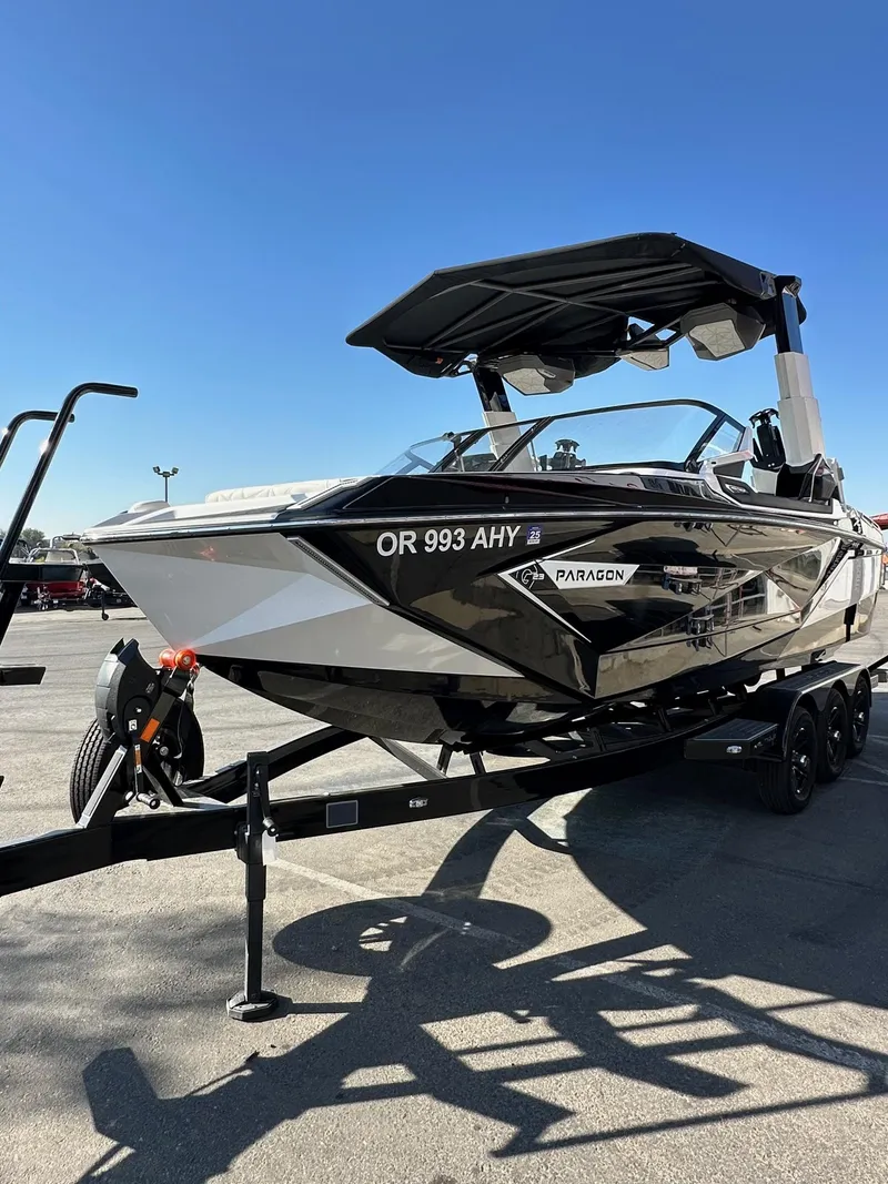 Slide: The Image of 2023 Nautique PARAGON 23 boat on trailer, black and white design, sunny day. - 6