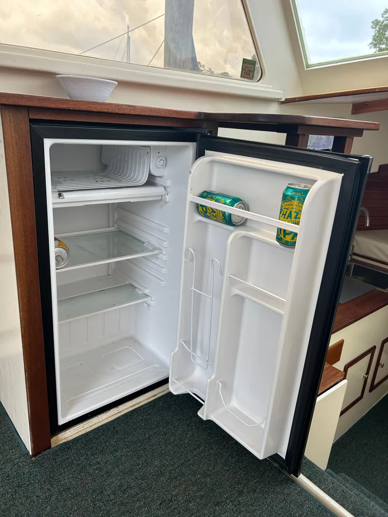Slide: The Image of Open fridge inside 1996 Mast & Mallet 34 Rabbit Custom boat, with drinks and shelves visible. - 18