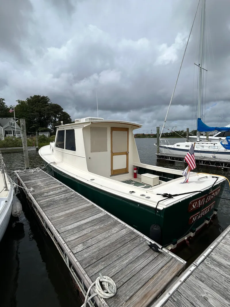 Slide: The Image of 1996 Mast & Mallet 34 Rabbit Custom boat docked, overcast sky, American flag displayed. - 5