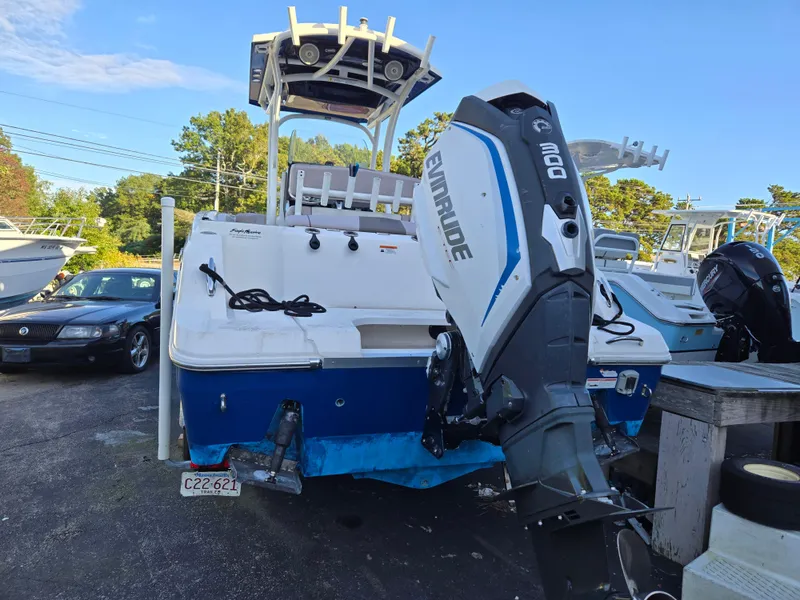 Slide: The Image of 2019 Wellcraft 242 Fisherman boat with Evinrude outboard motor, parked outdoors. - 2