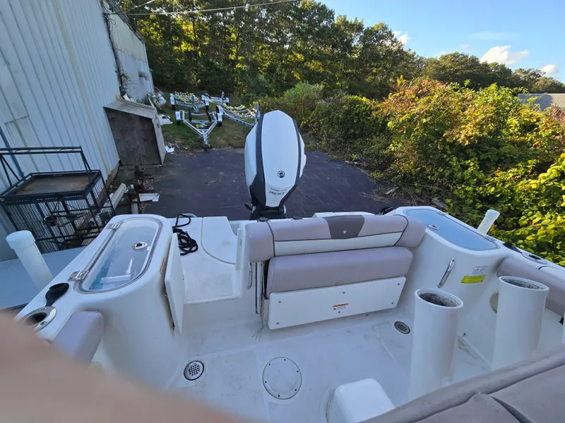 Slide: The Image of 2019 Wellcraft 242 Fisherman boat interior with seating and outboard motor, parked outdoors. - 3