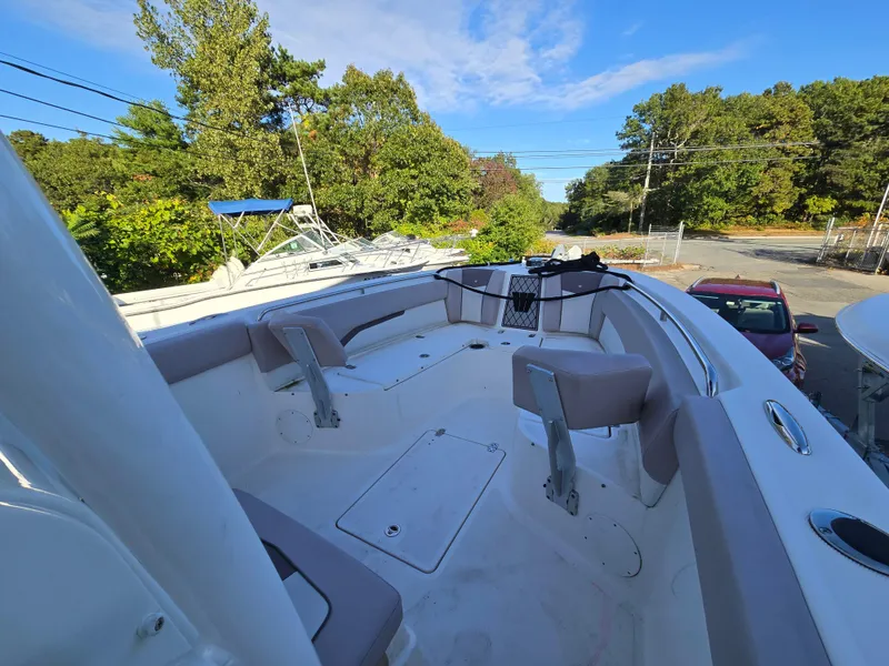 Slide: The Image of 2019 Wellcraft 242 Fisherman boat interior with seating, surrounded by trees and parked cars. - 5