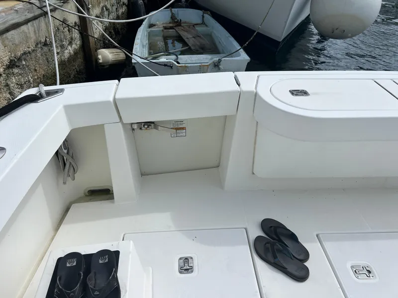 Slide: The Image of 2005 Rampage 45 Convertible boat deck with flip-flops, docked near a small dinghy. - 13