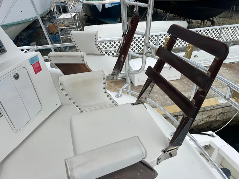 Slide: The Image of 2005 Rampage 45 Convertible boat with white seating and wooden ladder-back chair. - 47