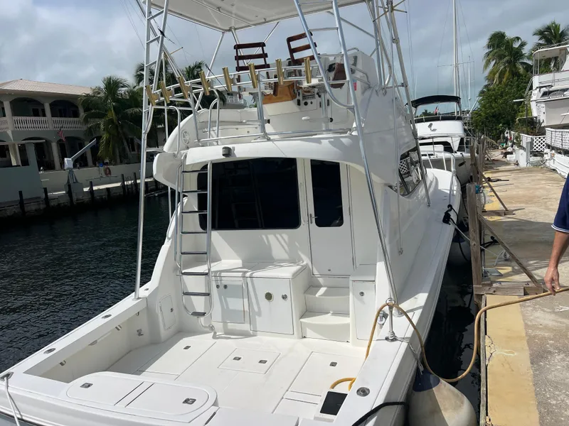 Slide: The Image of 2005 Rampage 45 Convertible yacht docked at marina, featuring spacious deck and ladder. - 8