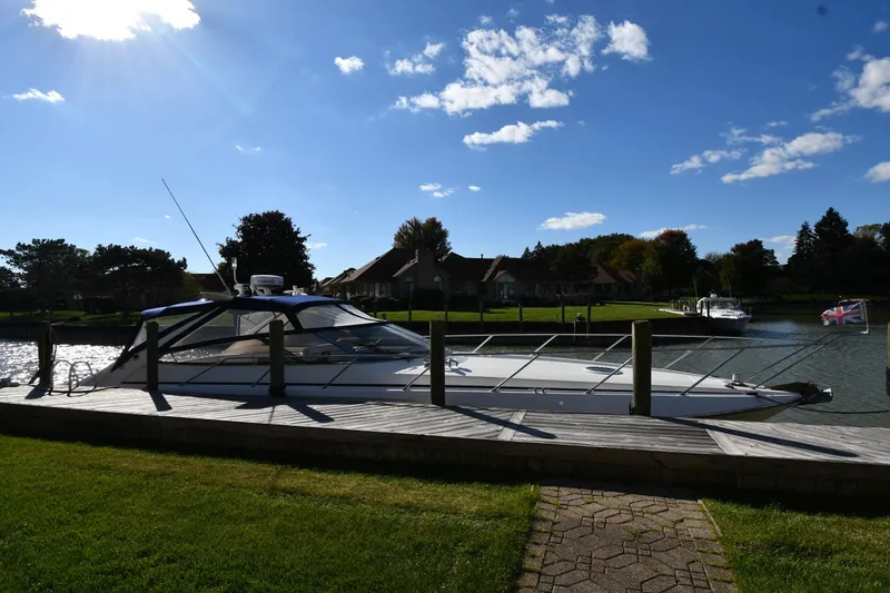 Slide: The Image of Sunseeker Camargue 47 yacht docked by a scenic riverside, under a clear blue sky. - 3
