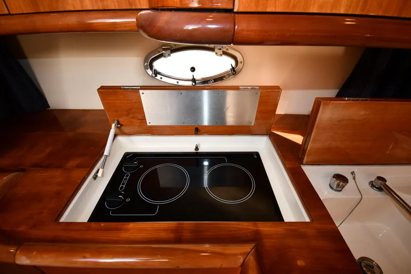 Slide: The Image of Sunseeker Camargue 47 yacht kitchen with electric stove, wooden cabinetry, and porthole window, 1997 model. - 53