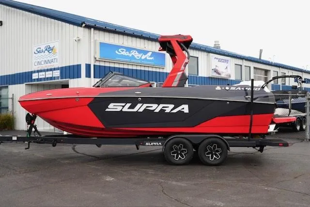 Slide: The Image of 2025 Supra SA 450 boat in red and black on trailer outside dealership. - 1